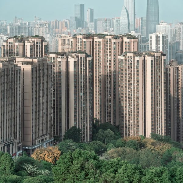 Aerial view of skyscrapers towering over green urban spaces in a modern cityscape.