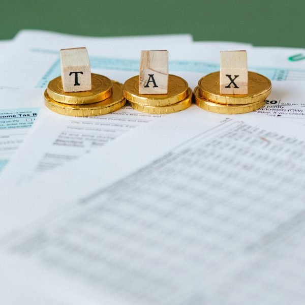 Staged image of gold coins with tax letter tiles on documents.
